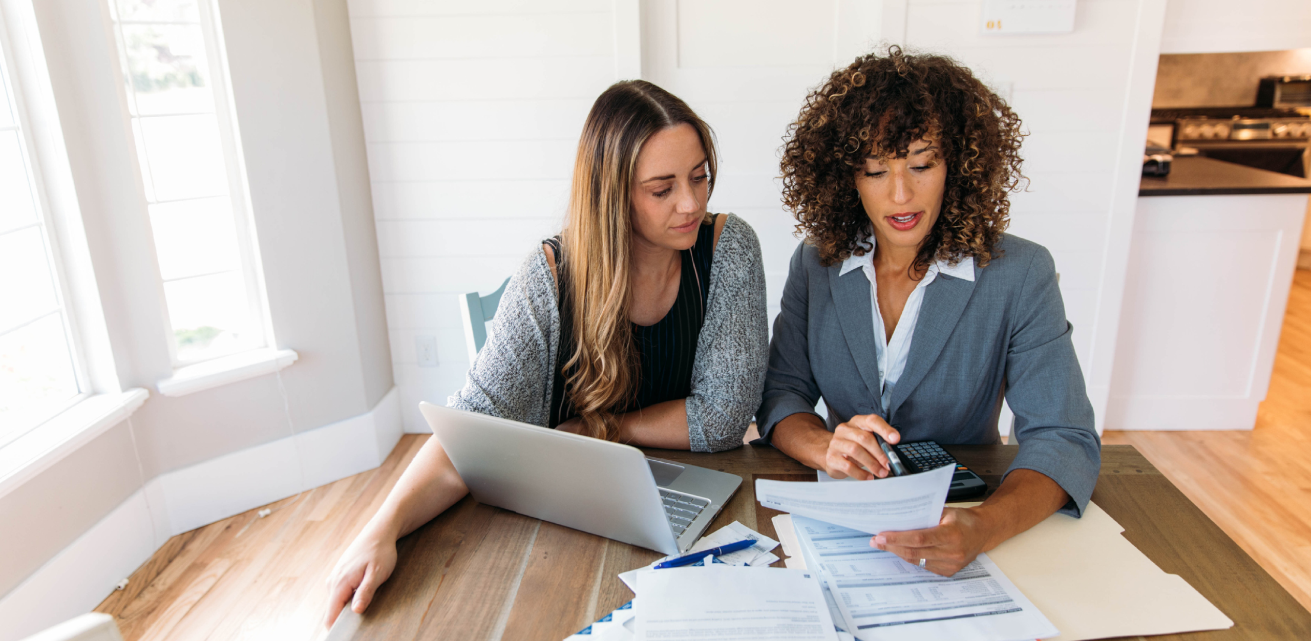 Two women are looking down at something and talking.