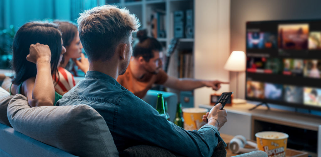 A group of friends are sitting in a room watching television.