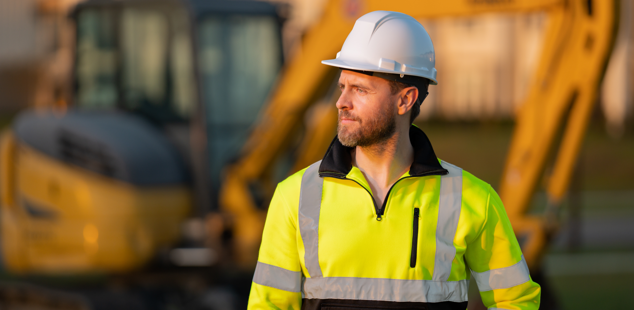 A man in a helmet stands in the middle of a construction site.