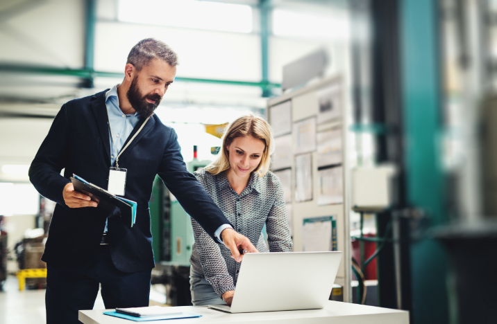 A man and a woman are working together on a laptop.