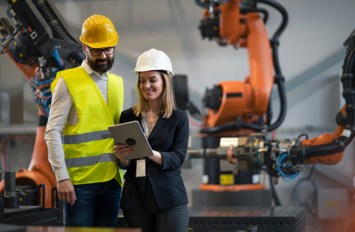A man and a woman are looking at a tablet. They are surrounded by robotics equipment.