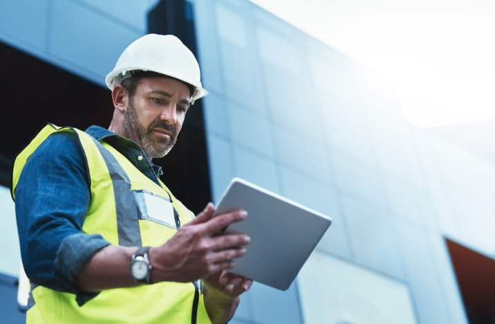 A construction worker is working on his tablet.