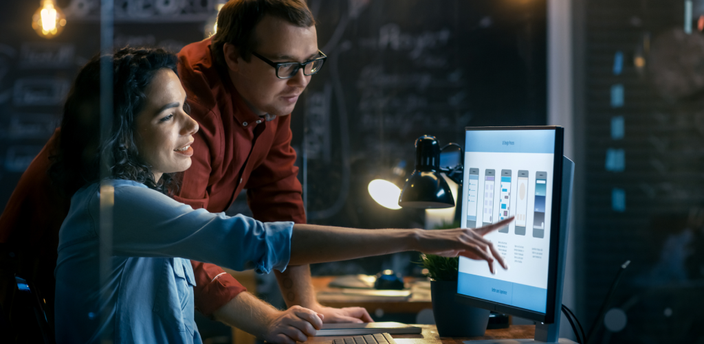 A man and a woman are talking as they look into a computer.