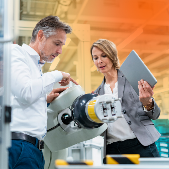 A man and a woman are pointing at machinery and talking.