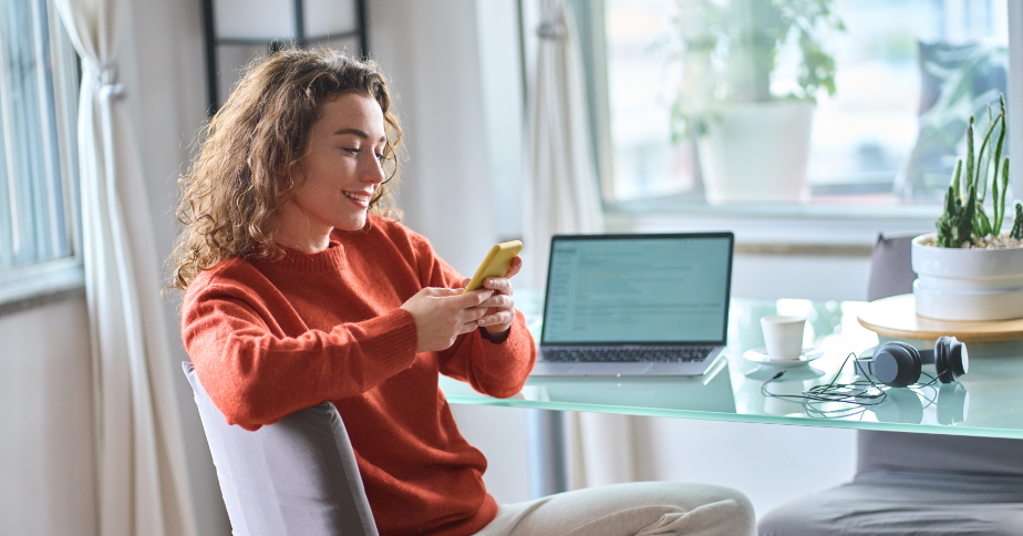 A woman is outside in an open area, looking at her phone.
