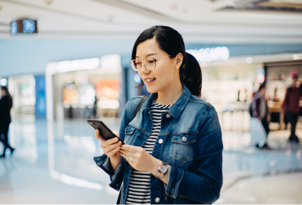 A woman is looking into her phone and smiling.