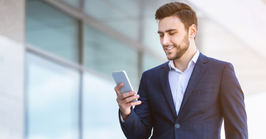A man is smiling at his phone.