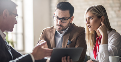 A man is looking into a tablet that is being held by a woman next to him.