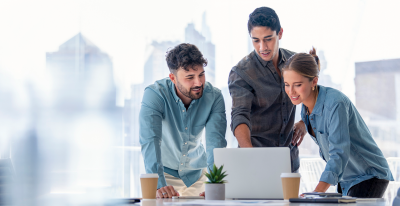 Two men and a woman are looking into a laptop together.