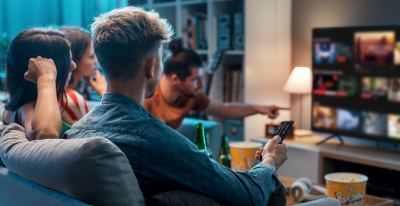 A group of friends are sitting in a room watching television.